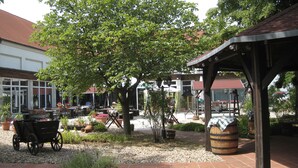 Un espace extérieur aménagé en terrasse, avec une pergola en bois, un chariot rustique et des plantes en pot.