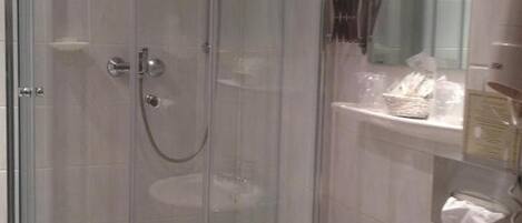 Une douche fermée par des parois de verre, avec un lavabo blanc et un miroir au-dessus.
