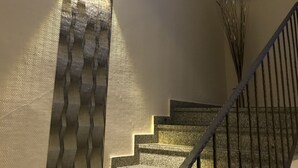Un escalier avec un mur à texture et un luminaire.