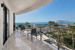 A balcony with a table and chairs, offering a view of the sea and a distant island. - Grand Uysal Beach&Spa Hotel - All inclusive (Alanya)