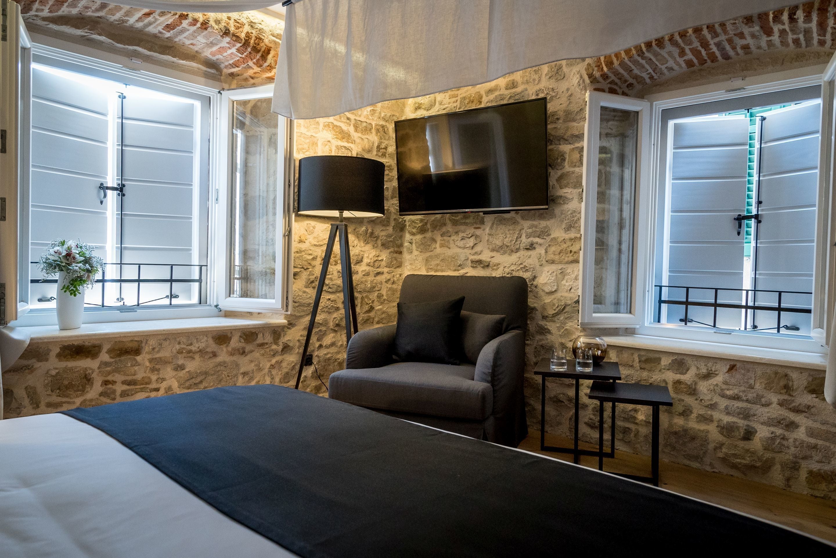 A bedroom with a bed, a chair, a TV, and a lamp.