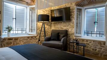 A bedroom with a bed, a chair, a TV, and a lamp.