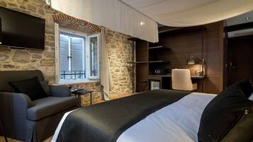 Habitación de hotel con pared de piedra, cama, sofá, escritorio y televisión.