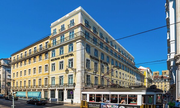 A historic building with multiple floors, labeled as a hotel. It features a prominent entrance with a sign, and a tram line running in front. - Pestana CR7 Lisboa (Lisbon)