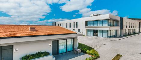 A modern building with a tiled roof, a covered patio with seating, and a landscaped garden area.