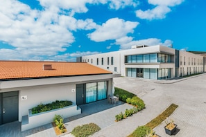 Ein modernes Gebäude mit Ziegeldach, einer überdachten Terrasse und einem angelegten Garten.
