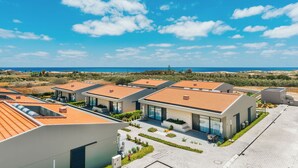 Un moderno complejo residencial con varias casas de techos planos, grandes ventanales y vista al mar.
