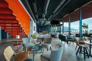 A modern interior with a staircase, seating areas, and large windows offering a view.