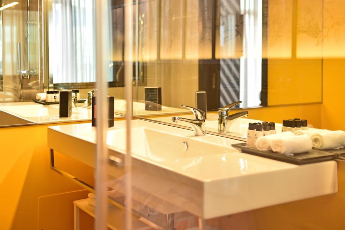 Un baño moderno con un espejo grande, dos lavamanos y artículos de aseo bien organizados.