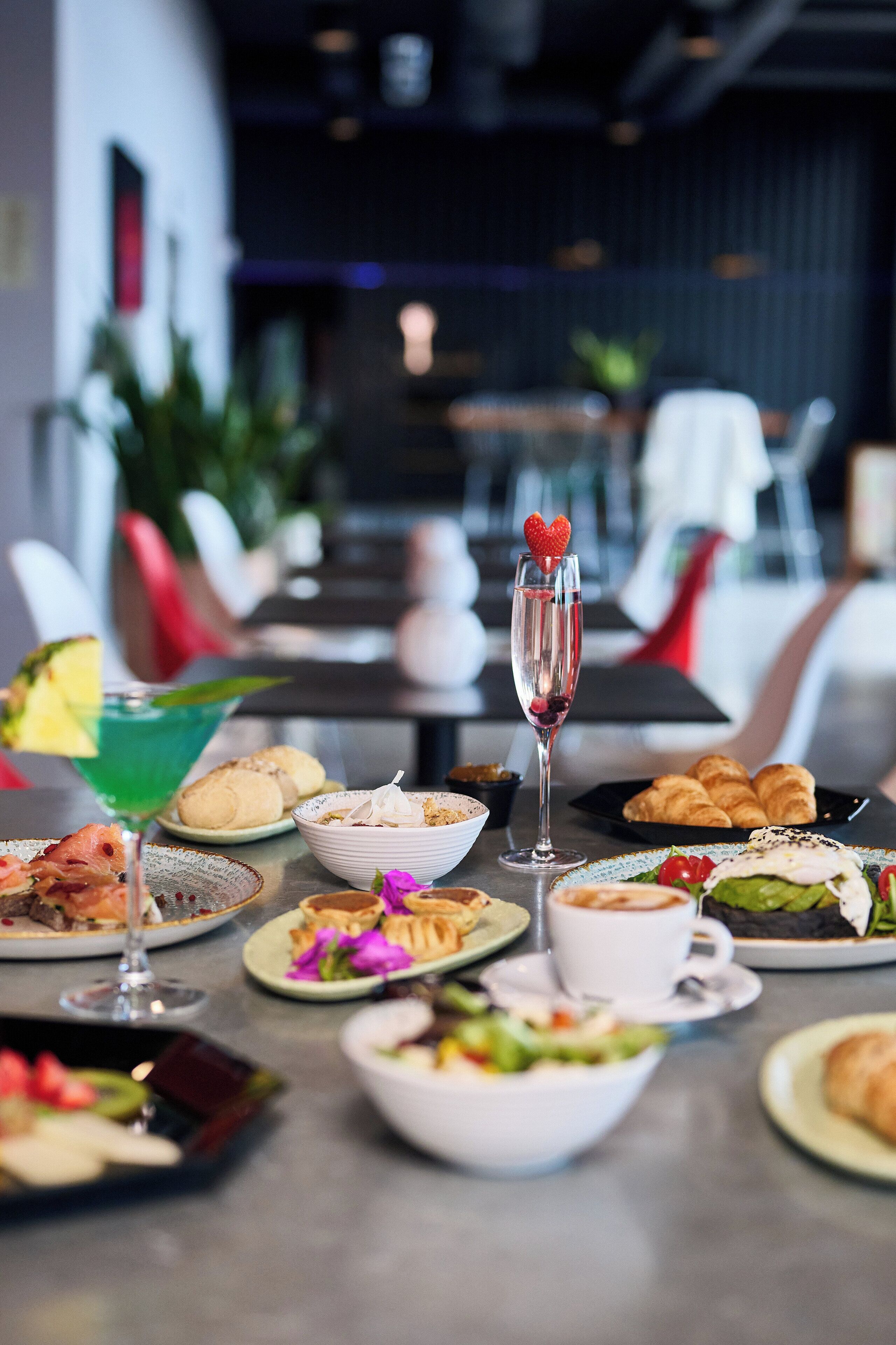 Une table à manger dressée avec différents plats, un cocktail et une coupe de champagne.