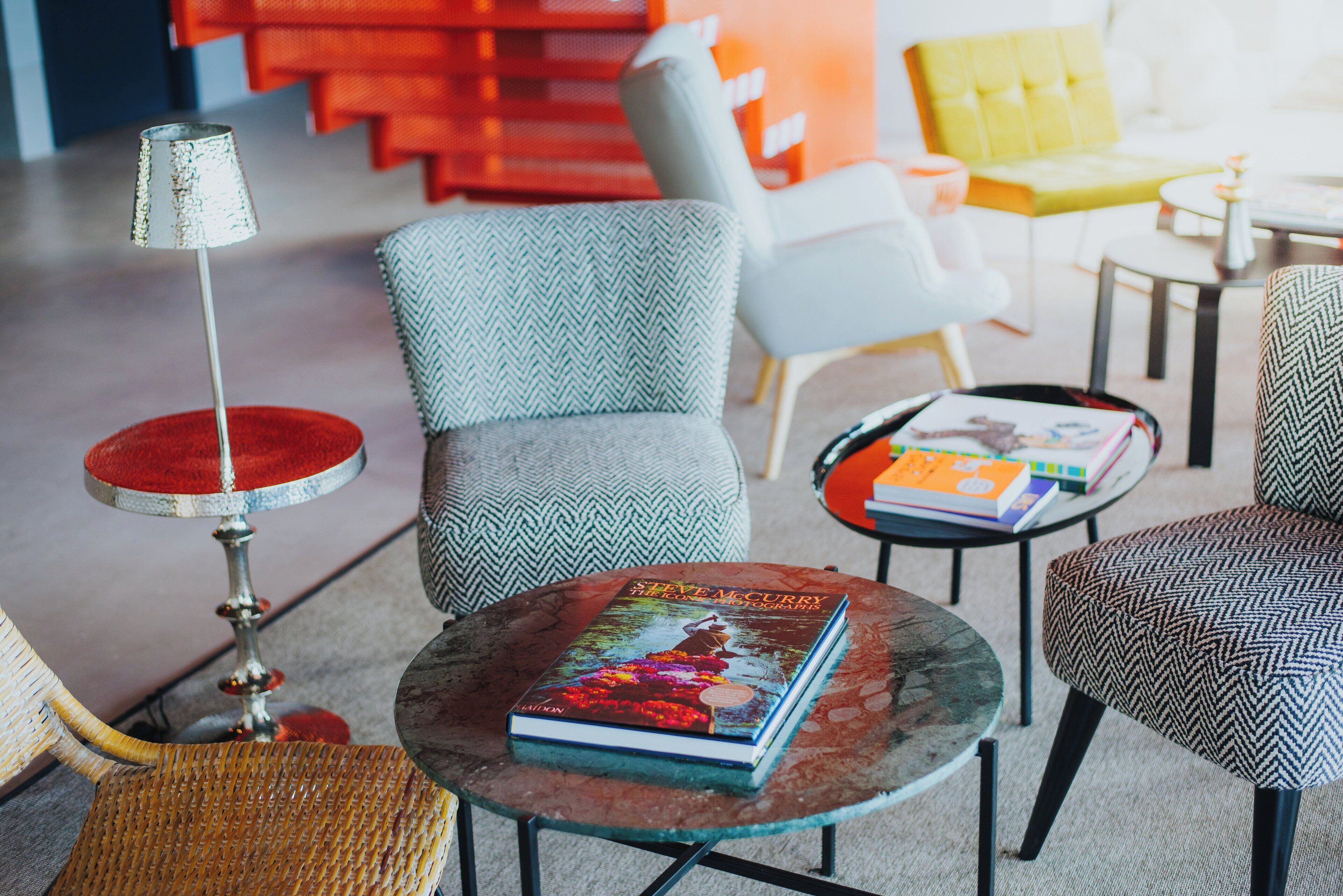 Un salon moderne avec un canapé, des fauteuils, une table basse sur laquelle repose un livre et une lampe.