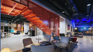 A modern interior with a central staircase, seating areas, and a bar/lounge area. - Pestana CR7 Funchal (Funchal)