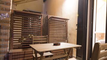 A rustic outdoor seating area with wooden furniture and a brick wall.