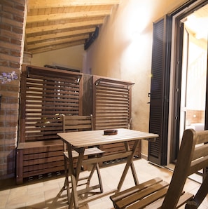 A rustic outdoor seating area with wooden furniture and a brick wall. - Bed & Breakfast Le Due G (Varese)