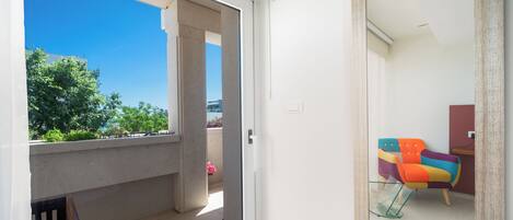 A room with a sliding glass door leading to a balcony, a colorful chair, and a small table.