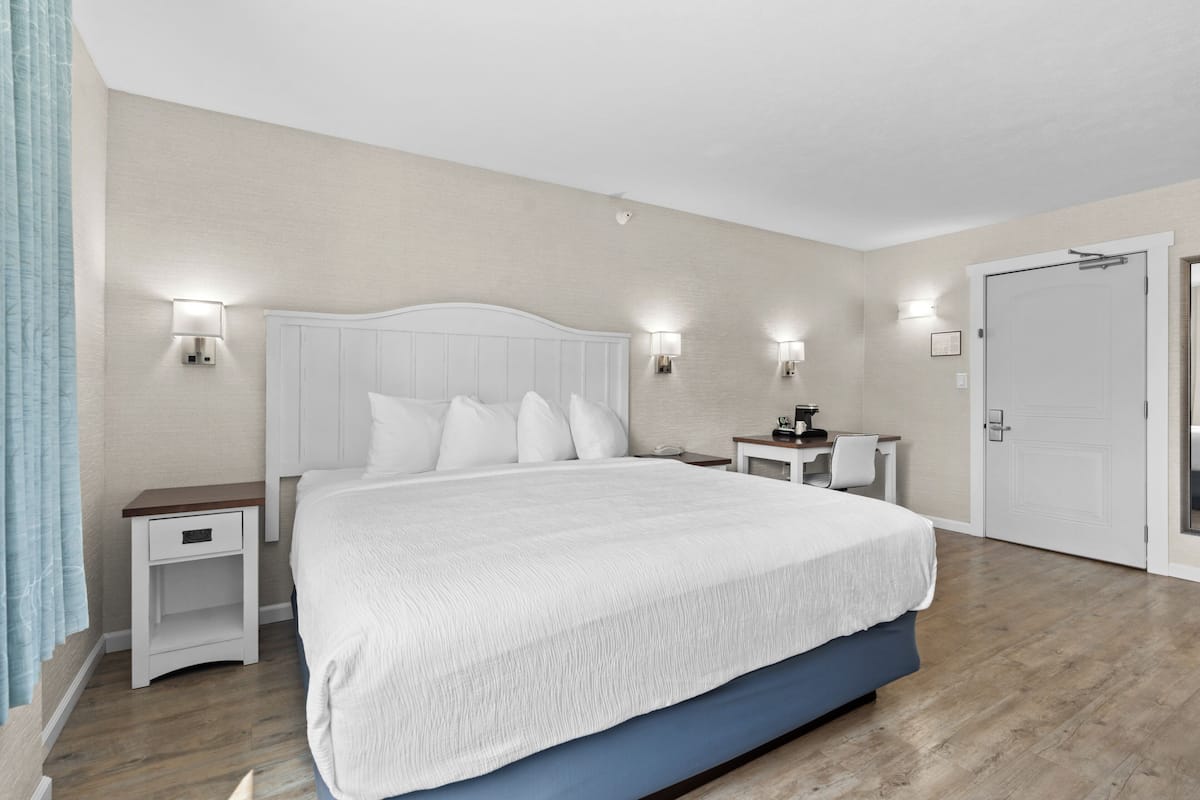 A bedroom with a large bed, bedside tables, a nightstand, and a door.