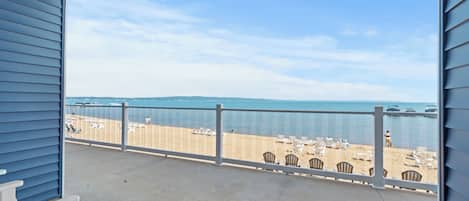 A balcony with a view of a beach and the ocean.
