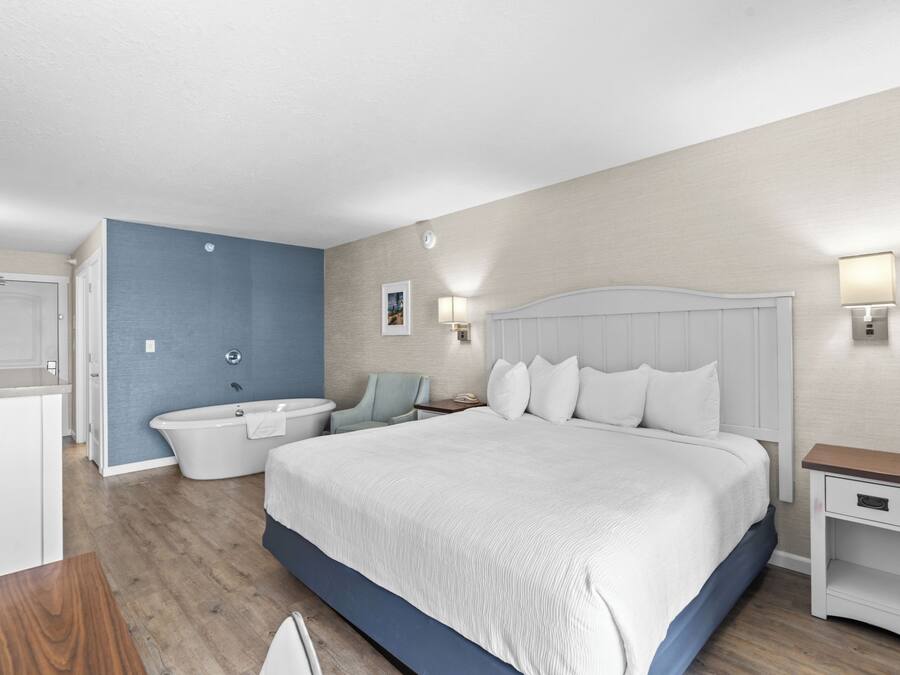 Una habitación de hotel moderna con una cama grande, una bañera, un escritorio y una silla.