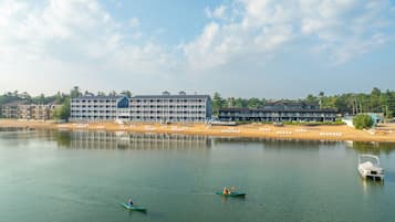 A waterfront hotel with multiple buildings, a sandy beach, and calm water.