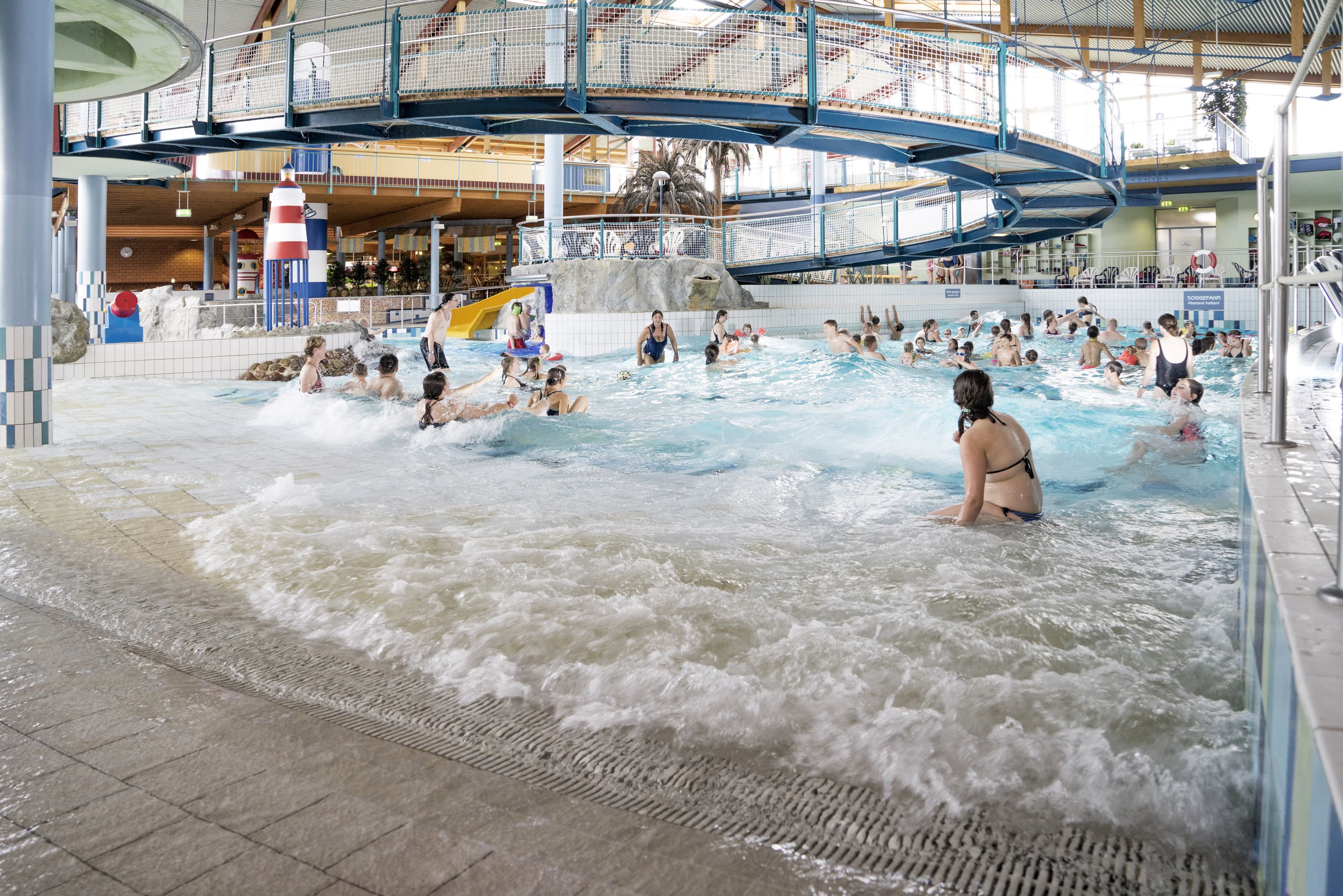 Una piscina interior con varias pistas de natación, un elemento acuático central y una plataforma de observación superior.