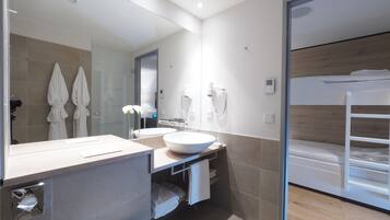 A modern bathroom with a large mirror, a sink, and a vanity. There are towels and a hairdryer on the wall.