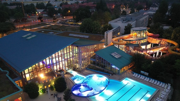 A swimming pool area with a large pool, a water slide, and a covered seating area.
