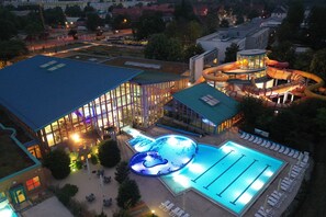 A swimming pool area with a large pool, a water slide, and a covered seating area. - Wonnemar Resort-Hotel (Wismar)