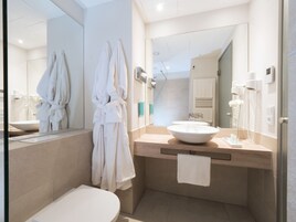 Un baño moderno con un espejo grande, un lavamanos y dos toallas blancas colgadas en la pared.