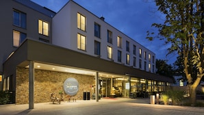 A modern hotel with a stone facade, large windows, and a well-lit entrance.