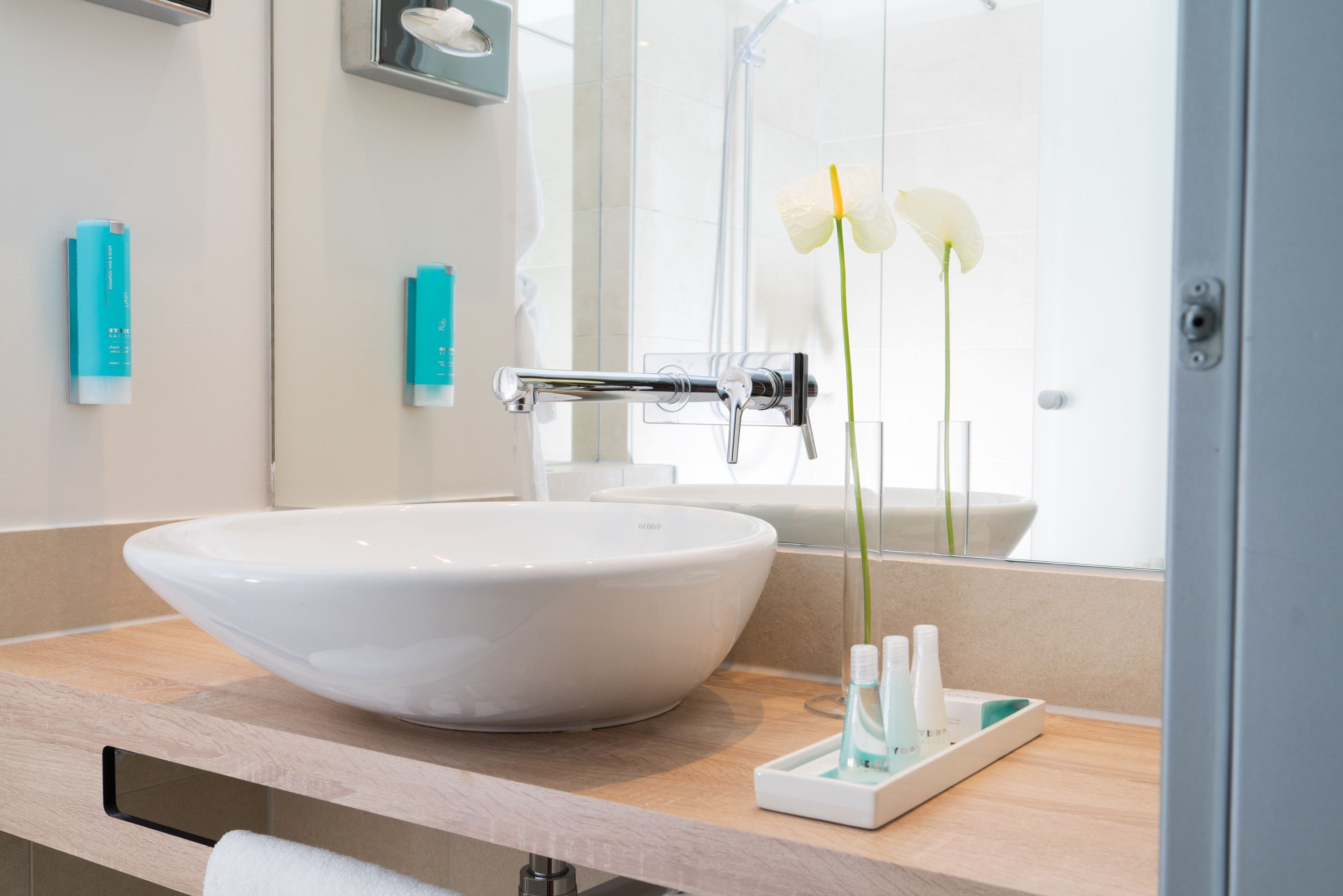 A bathroom with a white sink, a mirror, and a shower area.