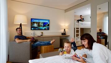 Una camera d'albergo moderna con TV a schermo piatto, un divano, un letto e una cuccetta.