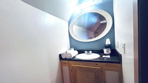 Un baño con lavamanos, espejo y armarios de madera.