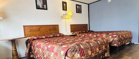 A room with two beds, a table, and a lamp.