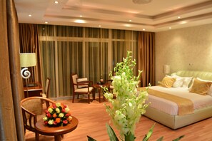 Una habitación de hotel con una cama, un escritorio, una silla y una mesa con un arreglo floral.