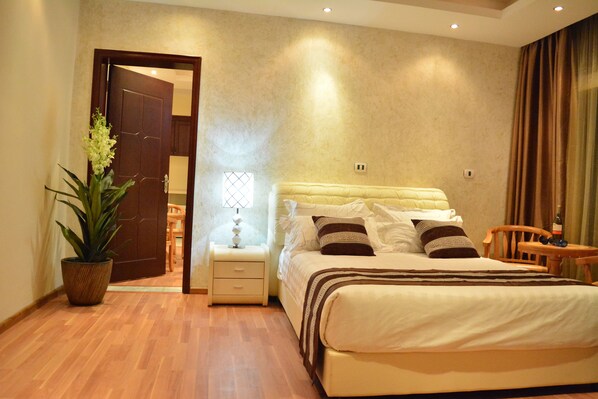 A bedroom with a bed, bedside table, lamp, and a potted plant.