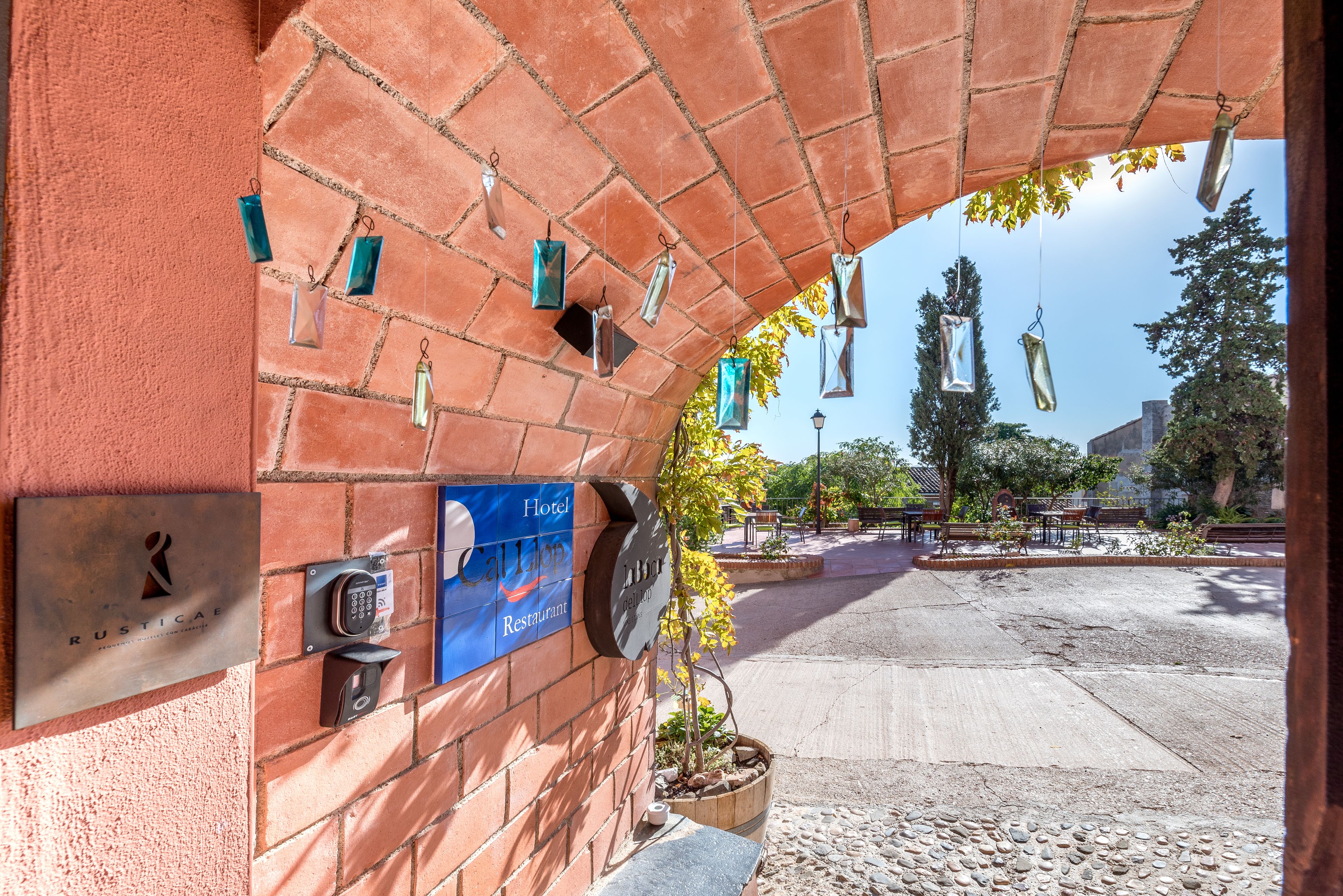 A brick wall with a plaque reading "Rusticae Hotel Restaurant" and a keypad for room access.