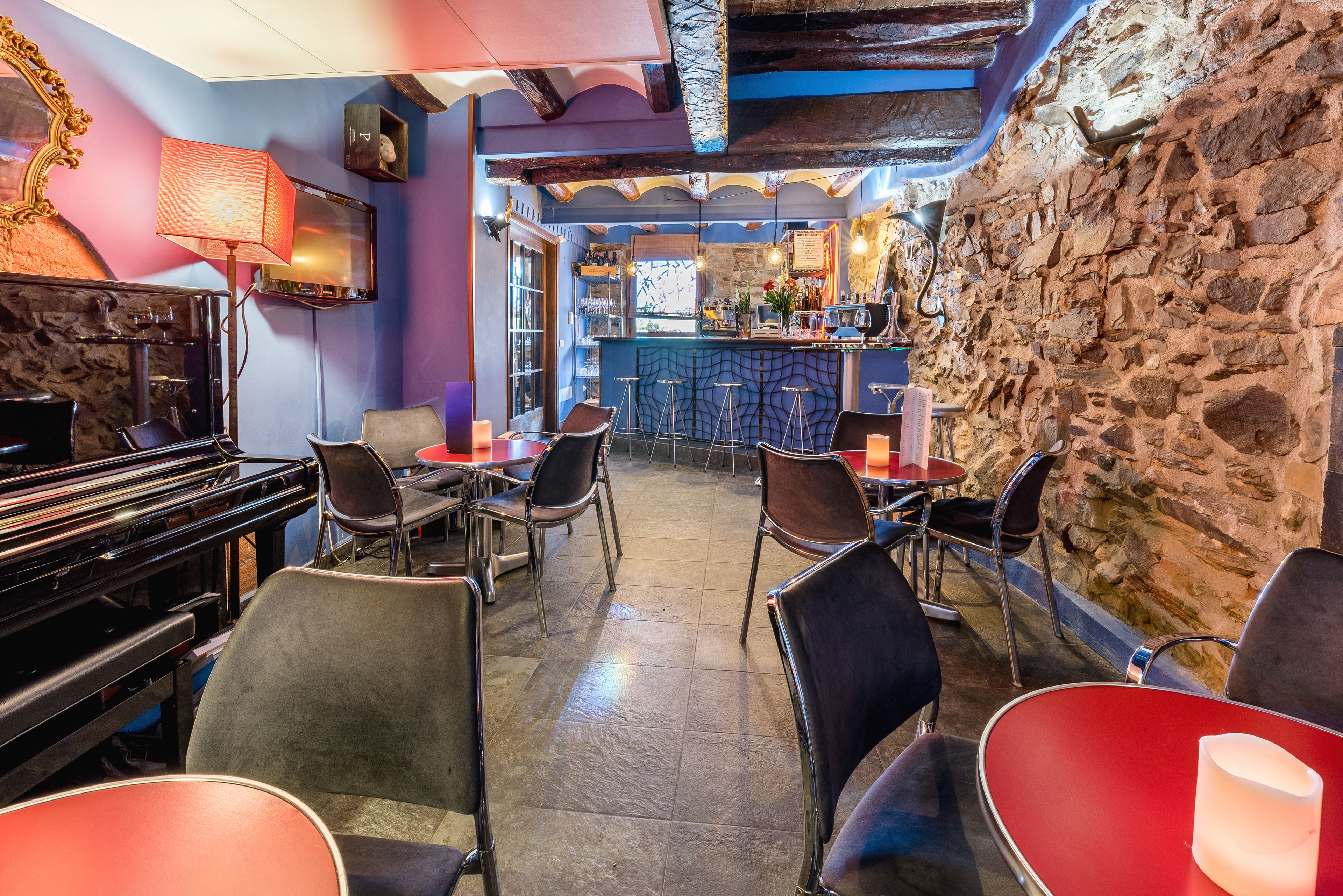 Un restaurante con piano, zona de bar y paredes de piedra.