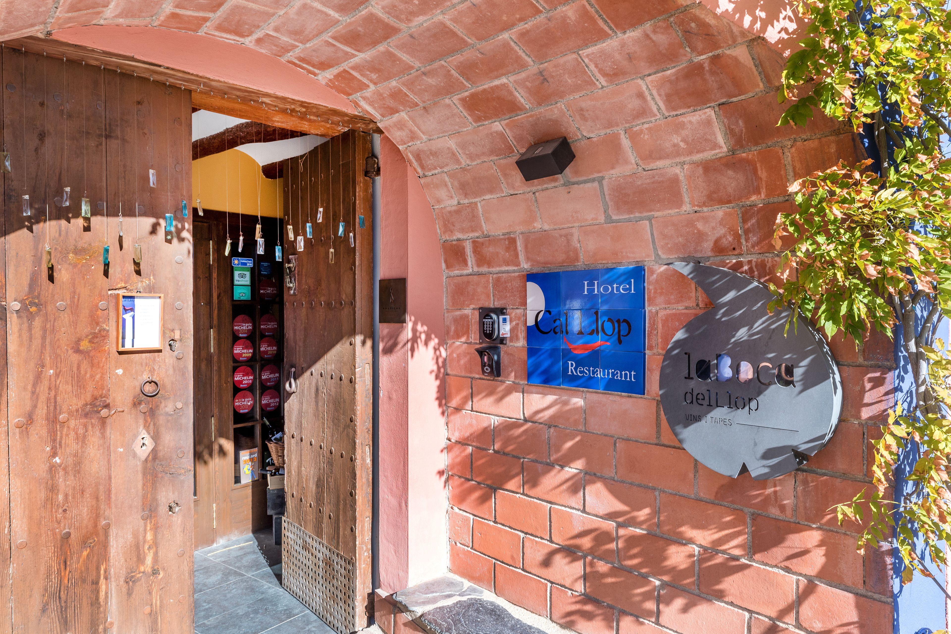 Entrada de hotel con puerta de madera, un letrero que dice 'Hotel Callop Restaurant' y una pared de ladrillo.