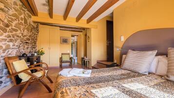 A bedroom with a bed, a chair, a desk, and a stone wall.