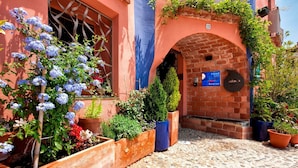 Un edificio con un arco de ladrillo, una ventana con celosía y un letrero que indica un hotel y restaurante.