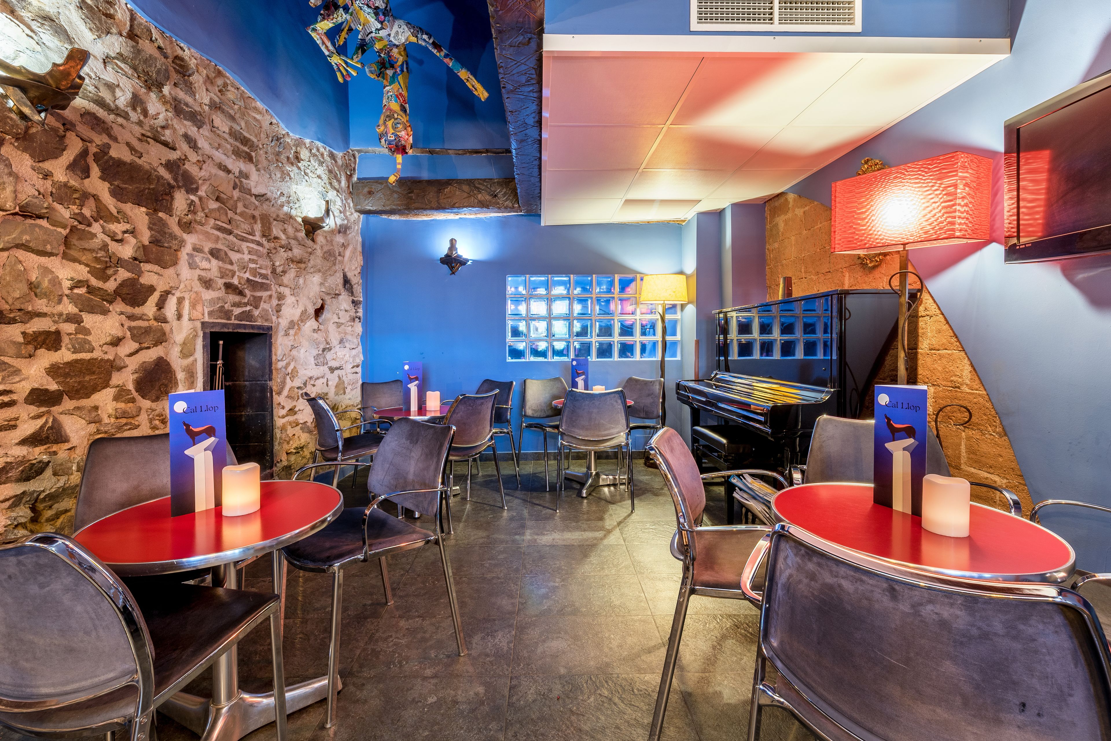 Een restaurant met stenen muren, rode tafels en stoelen.