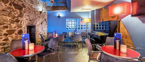 Een restaurant met stenen muren, rode tafels en stoelen.