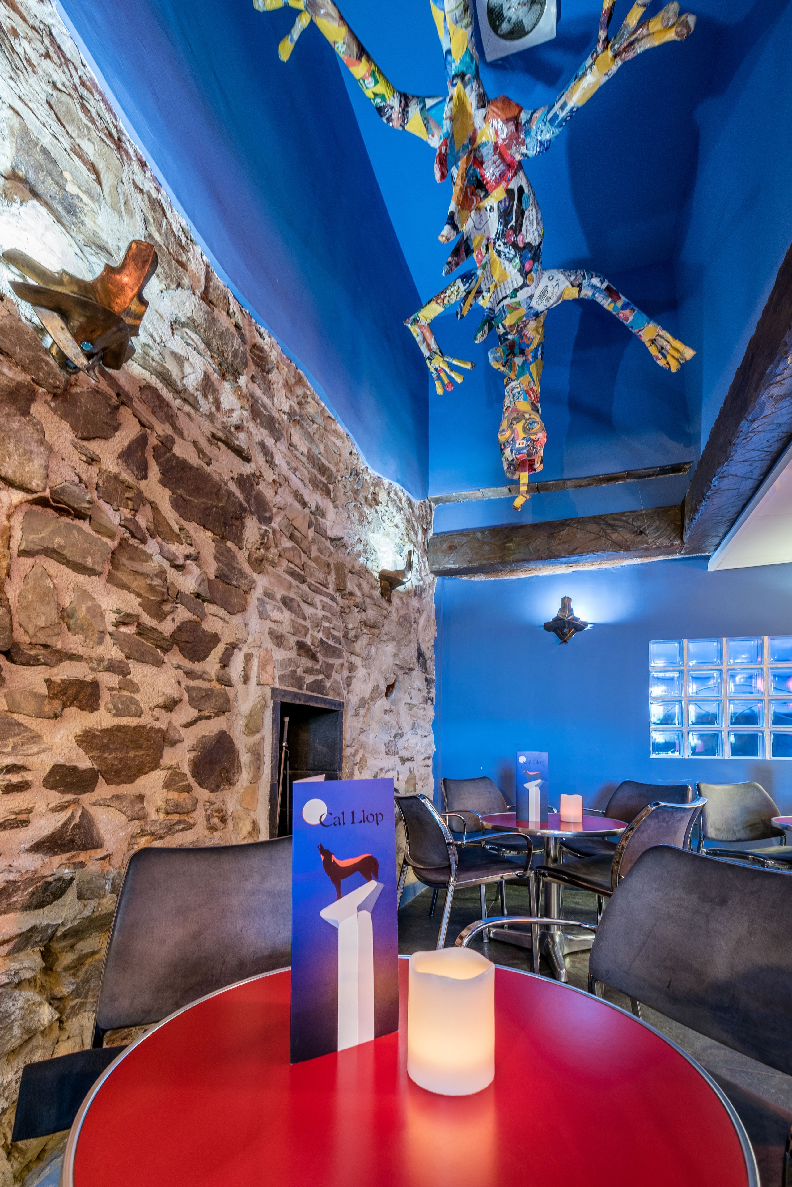 Una habitación con paredes de piedra, techo azul y una mesa con una vela.