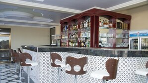 A bar area with a patterned wall, a wine cooler, and bar stools. - Rungwe Hotel (Dar es Salaam)