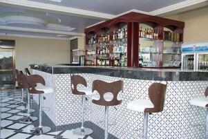 Zona de bar con pared decorativa, enfriador de vinos y taburetes.