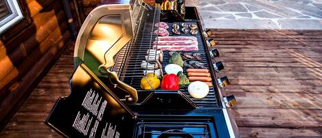 A barbecue grill with various meats and vegetables on a wooden deck.
