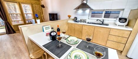 Una cocina moderna con armarios de madera, una campana extractora de acero inoxidable y una zona de comedor con una mesa dispuesta para dos.