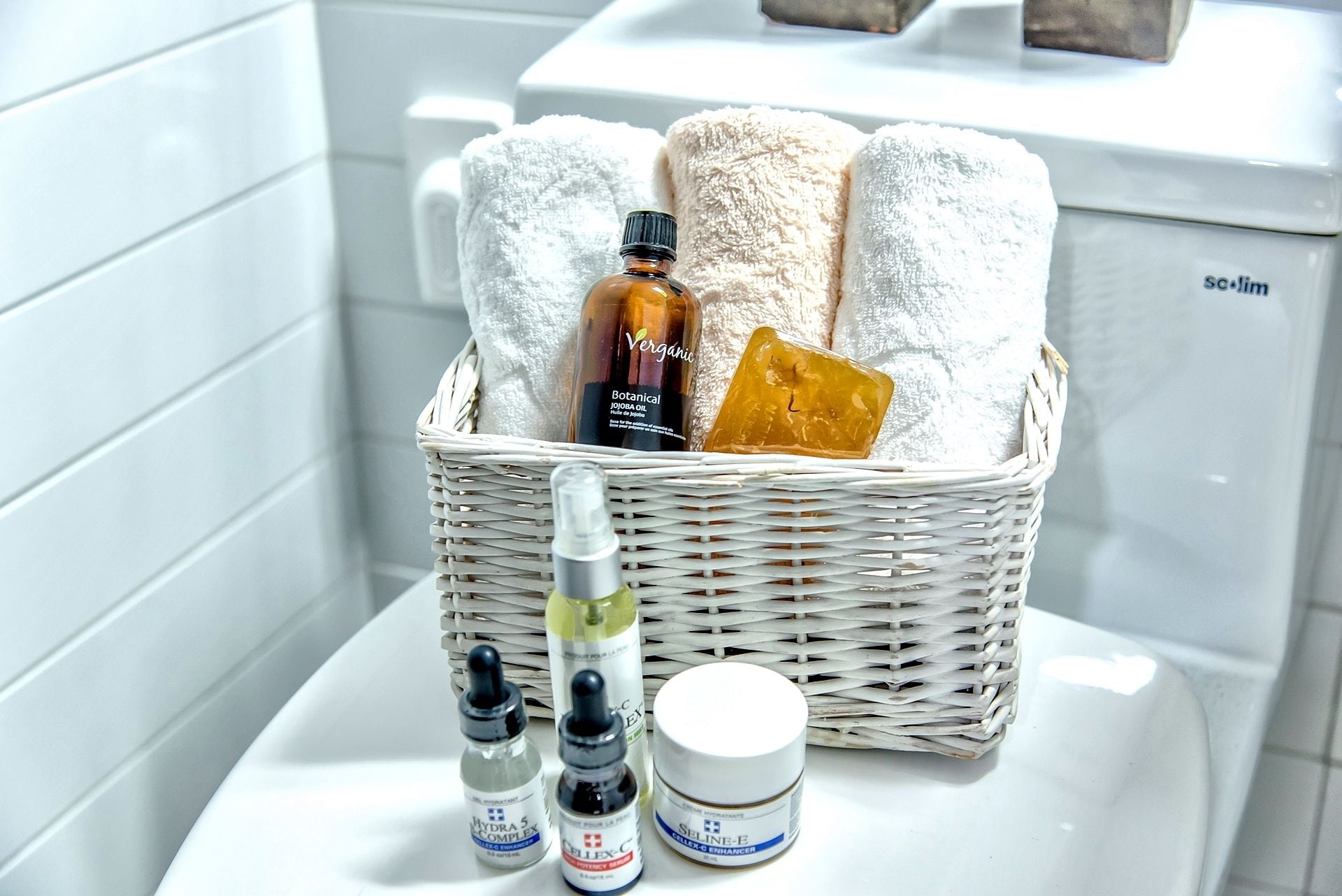 Un baño con una bañera blanca, una cesta de mimbre con artículos de aseo y una toalla blanca.