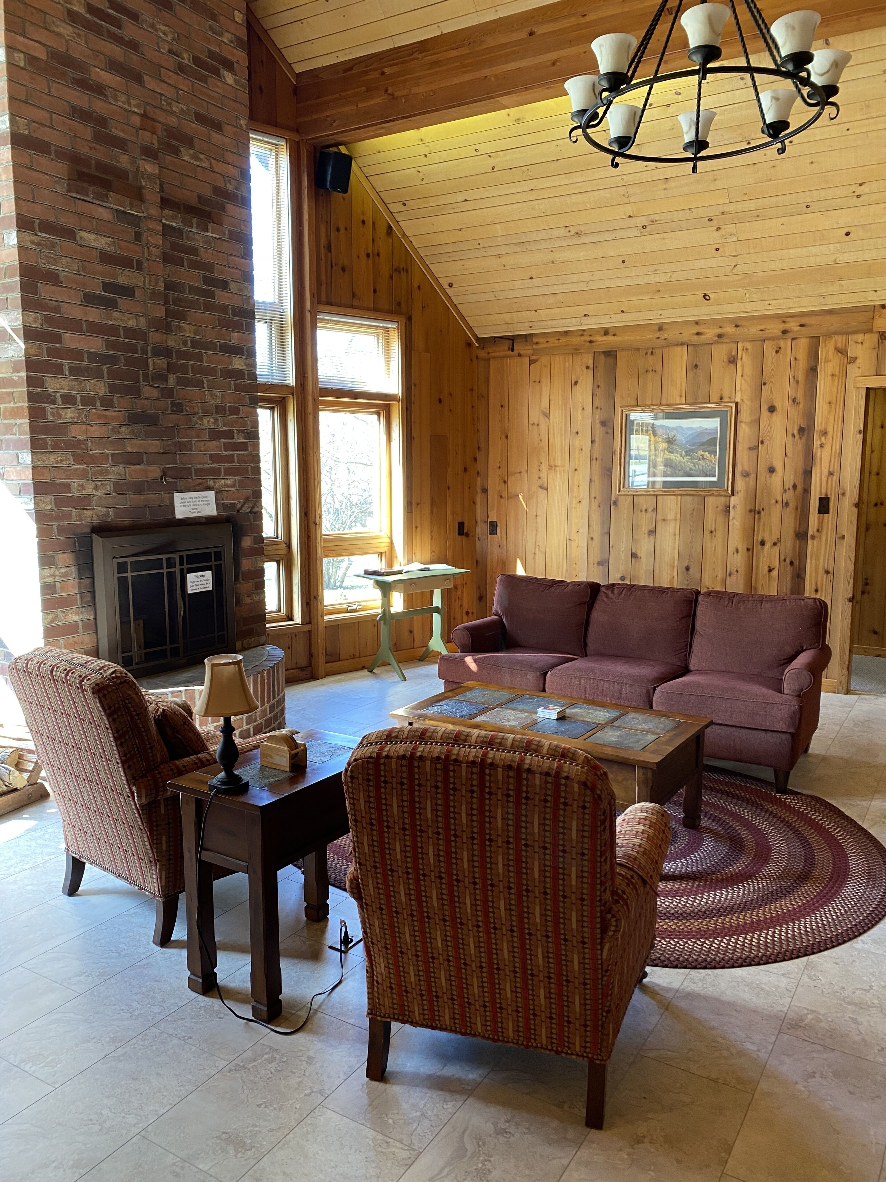 Een gezellige woonkamer met een open haard, houten wanden en een groot raam.