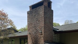 Eine Außenküche aus Ziegelsteinen mit Schornstein, Picknicktischen und einem gepflasterten Weg.